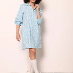 Woman wearing the Maude Vivante Ava Dress in Carolina Blue, featuring a vibrant blue print, collared button-front design, three-quarter balloon sleeves, contrast trim, and a relaxed A-line silhouette.