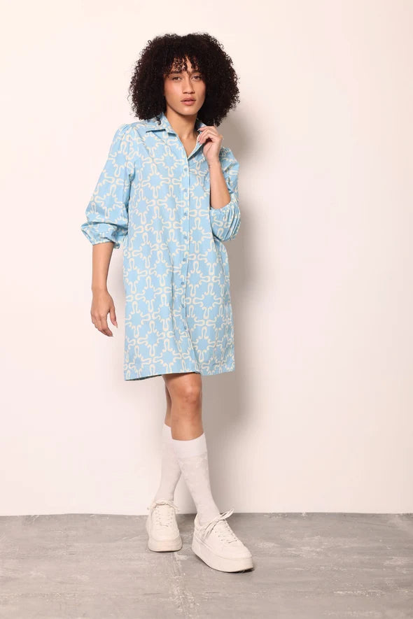 Woman wearing the Maude Vivante Ava Dress in Carolina Blue, featuring a vibrant blue print, collared button-front design, three-quarter balloon sleeves, contrast trim, and a relaxed A-line silhouette.