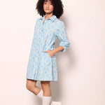 
Woman wearing the Maude Vivante Ava Dress in Carolina Blue, featuring a vibrant blue print, collared button-front design, three-quarter balloon sleeves, contrast trim, and a relaxed A-line silhouette.