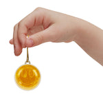 Hand holding a round yellow pendant with a smiley face design on a white background