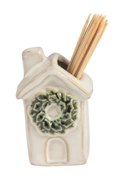 Four small ceramic toothpick holders shaped like a house with a green wreath, a snowman, a Santa figure, and a Christmas tree, arranged in a row on a white background.