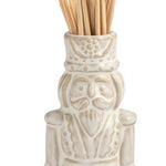 Four small ceramic toothpick holders shaped like a house with a green wreath, a snowman, a Santa figure, and a Christmas tree, arranged in a row on a white background.
