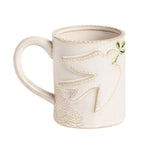 An off-white ceramic coffee mug featuring an embossed dove design with a small green leaf accent on the side, set against a plain white background.