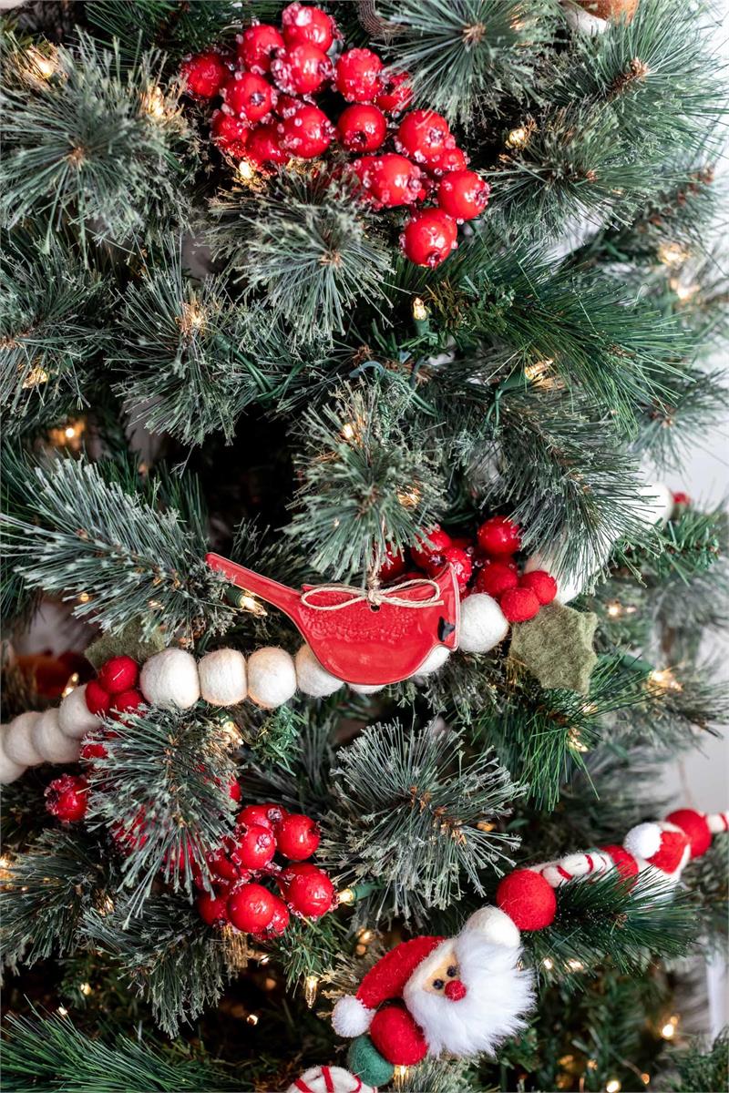 A close-up of a decorated Christmas tree with green branches, red berries, and red-and-white striped ornaments.