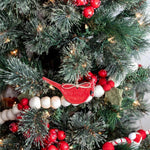 A close-up of a decorated Christmas tree with green branches, red berries, and red-and-white striped ornaments.