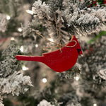 Red cardinal ornament on a snow-covered Christmas tree