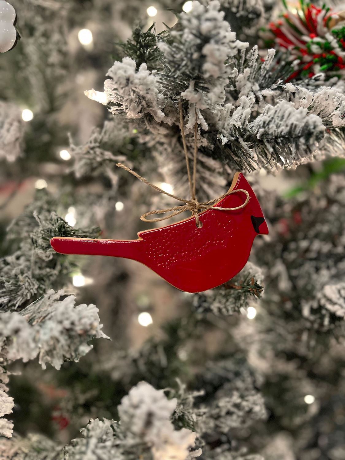 Red cardinal ornament on a snow-covered Christmas tree
