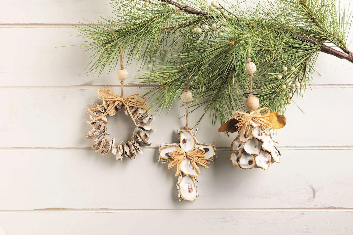 Decorative Christmas ornaments on a branch with pine needles on a light wooden background