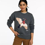 A woman wearing a dark gray knit crewneck sweater with a large embroidered pheasant graphic on the front, paired with brown pants, against a plain white background.