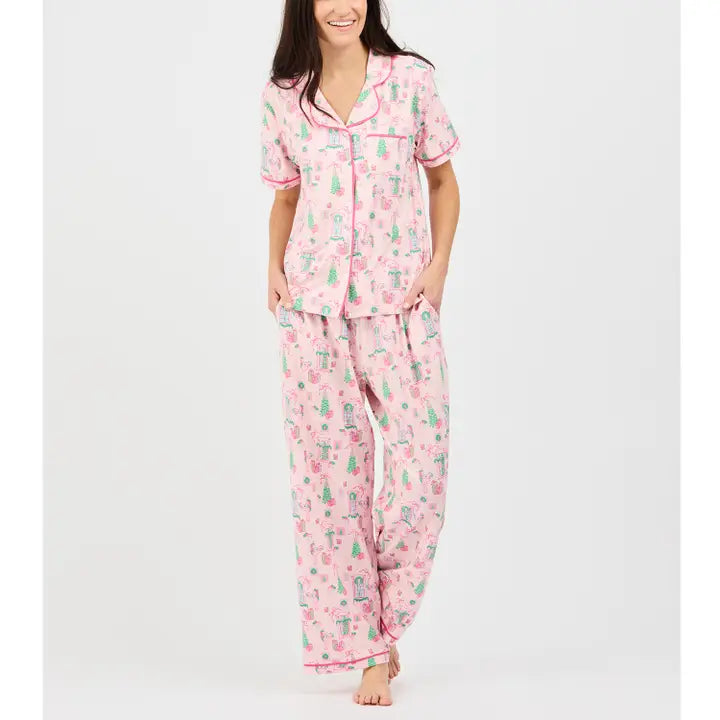 Mary Square Christmas Cottage Short Sleeve Pajama Set featuring a soft pink Christmas print with green and red accents, button-front top, pink piping, and coordinating pants.