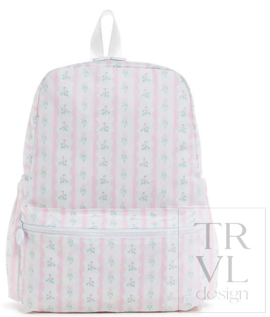 A white backpack featuring vertical pink stripes and a repeating light blue floral pattern, with a top carry loop and a front zippered pocket. A translucent 'TRVL design' watermark is visible on the bottom right.