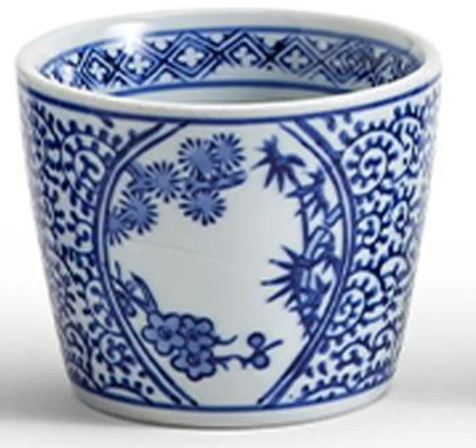 A white ceramic cup or small planter decorated with blue floral and botanical patterns in an oval medallion design, shown on a light gray background.