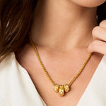 Gold necklace with green gemstones worn by a person