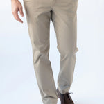 A person wearing beige straight-leg chinos with a blue t-shirt and brown leather shoes, shown from the waist down against a white studio background.