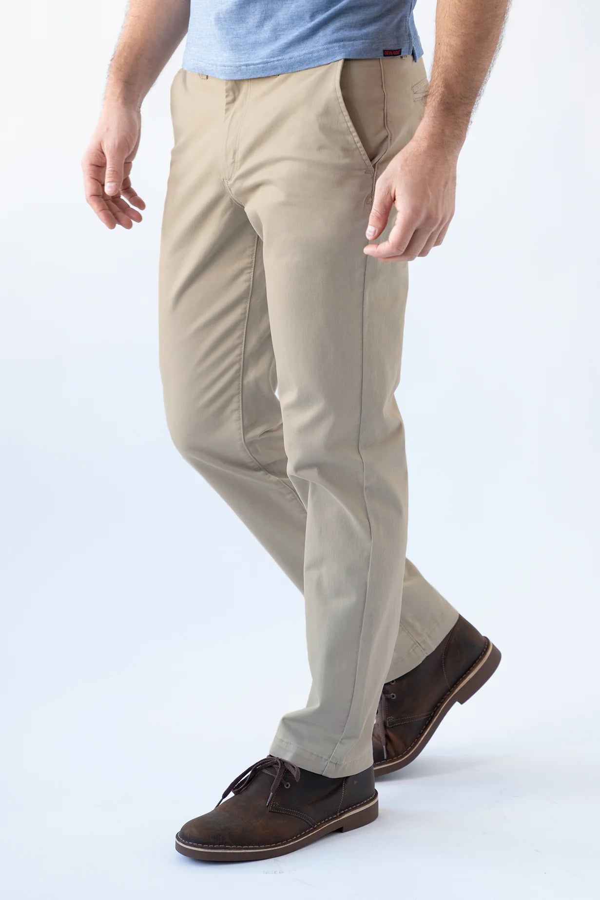 Person wearing beige pants and brown shoes on a white background