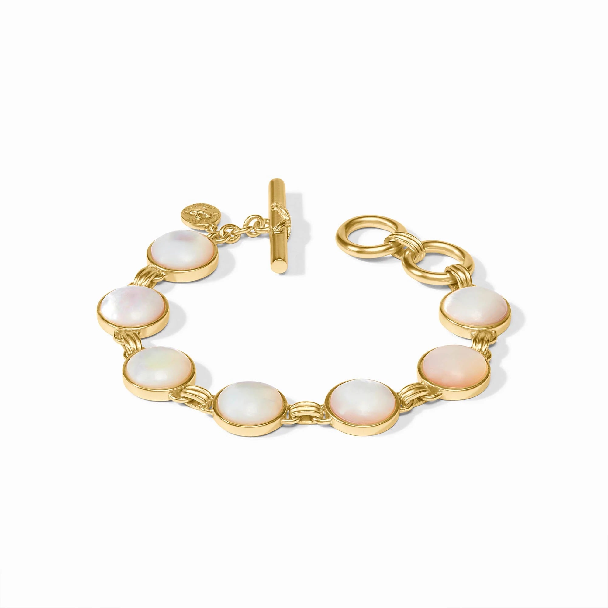 A gold-tone bracelet featuring seven oval iridescent white mother-of-pearl cabochons, a toggle clasp, and a small round logo charm, displayed on a clean white background.