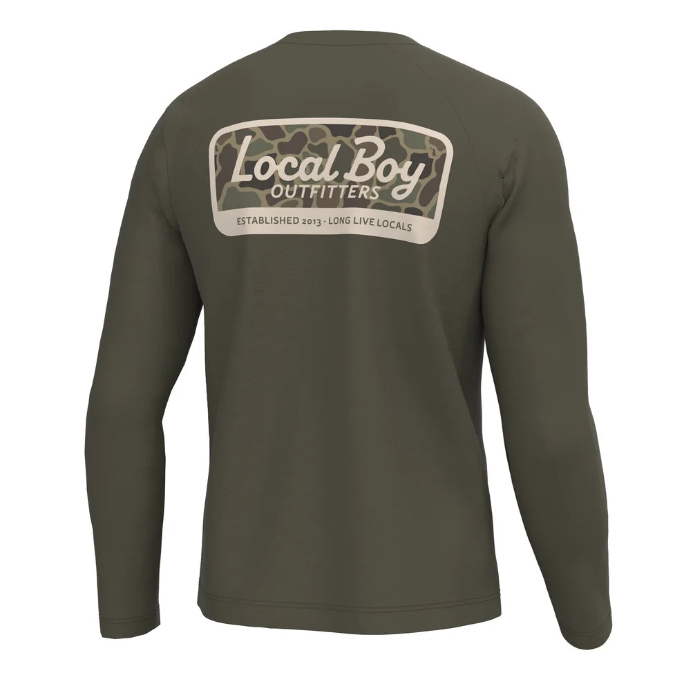 An olive green long-sleeve t-shirt shown from the back, featuring a large graphic print on the upper back with a camouflage pattern and the text 'Local Boy OUTFITTERS'.