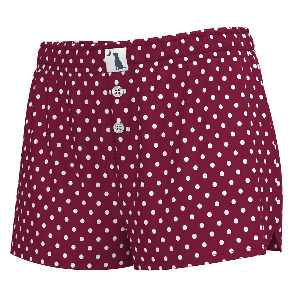 A pair of women's shorts in burgundy with a white polka dot pattern, featuring a button-fly front and a small white brand label on the waistband.