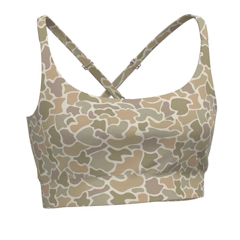 A women's sports bra with a desert camouflage pattern in shades of beige, tan, and light brown, featuring adjustable crossover back straps with silver metal buckles, shown on a plain white background.