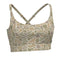 A women's sports bra with a desert camouflage pattern in shades of beige, tan, and light brown, featuring adjustable crossover back straps with silver metal buckles, shown on a plain white background.