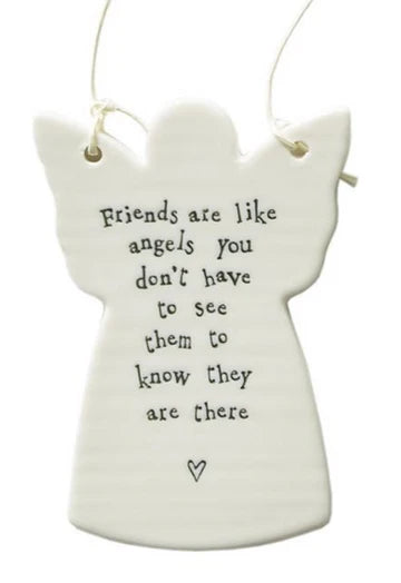 A white ceramic angel-shaped hanging ornament with black printed text that reads, 'Friends are like angels you don't have to see them to know they are there' and a small heart at the bottom, shown on a white background.