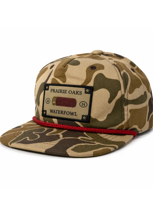 Prairie Oaks Waterfowl Shotshell Label Rope Hat in camouflage with shotshell logo patch, red rope detail, and flat bill.