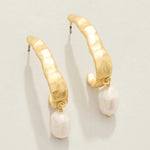 Gold hoop earrings with pearl drops on a light gray background