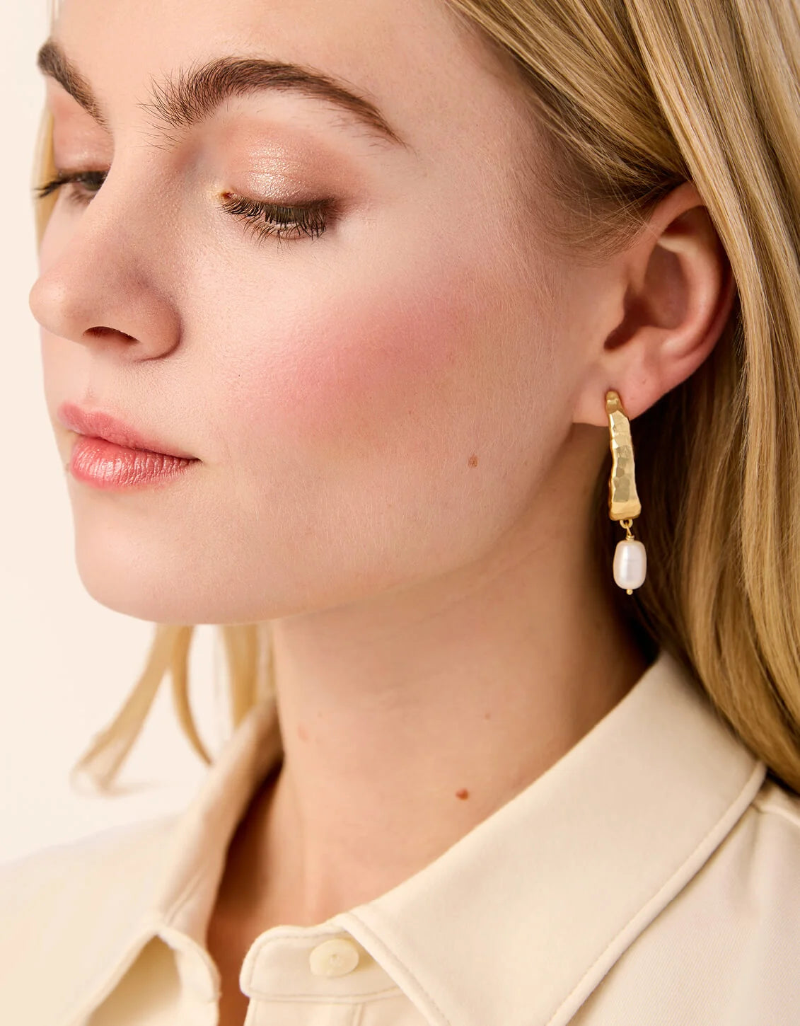 Close-up of a woman wearing gold earrings with a light background