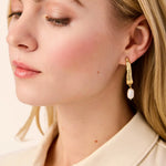 Close-up of a woman wearing gold earrings with a light background