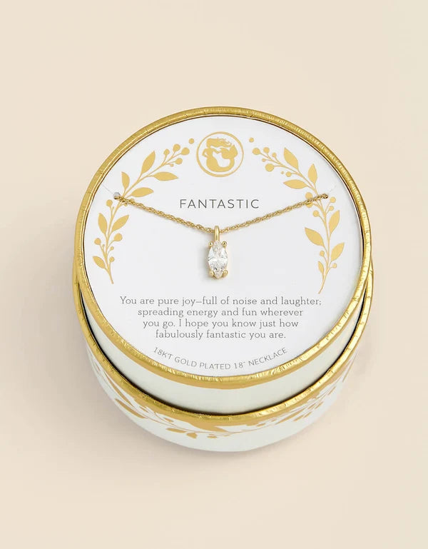 A gold-plated 18-inch necklace with a clear crystal pendant, presented on a white and gold round gift box with the word 'FANTASTIC' printed on the card insert, set against a solid beige background.