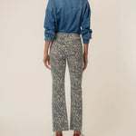Person wearing a blue denim shirt and patterned pants on a beige background