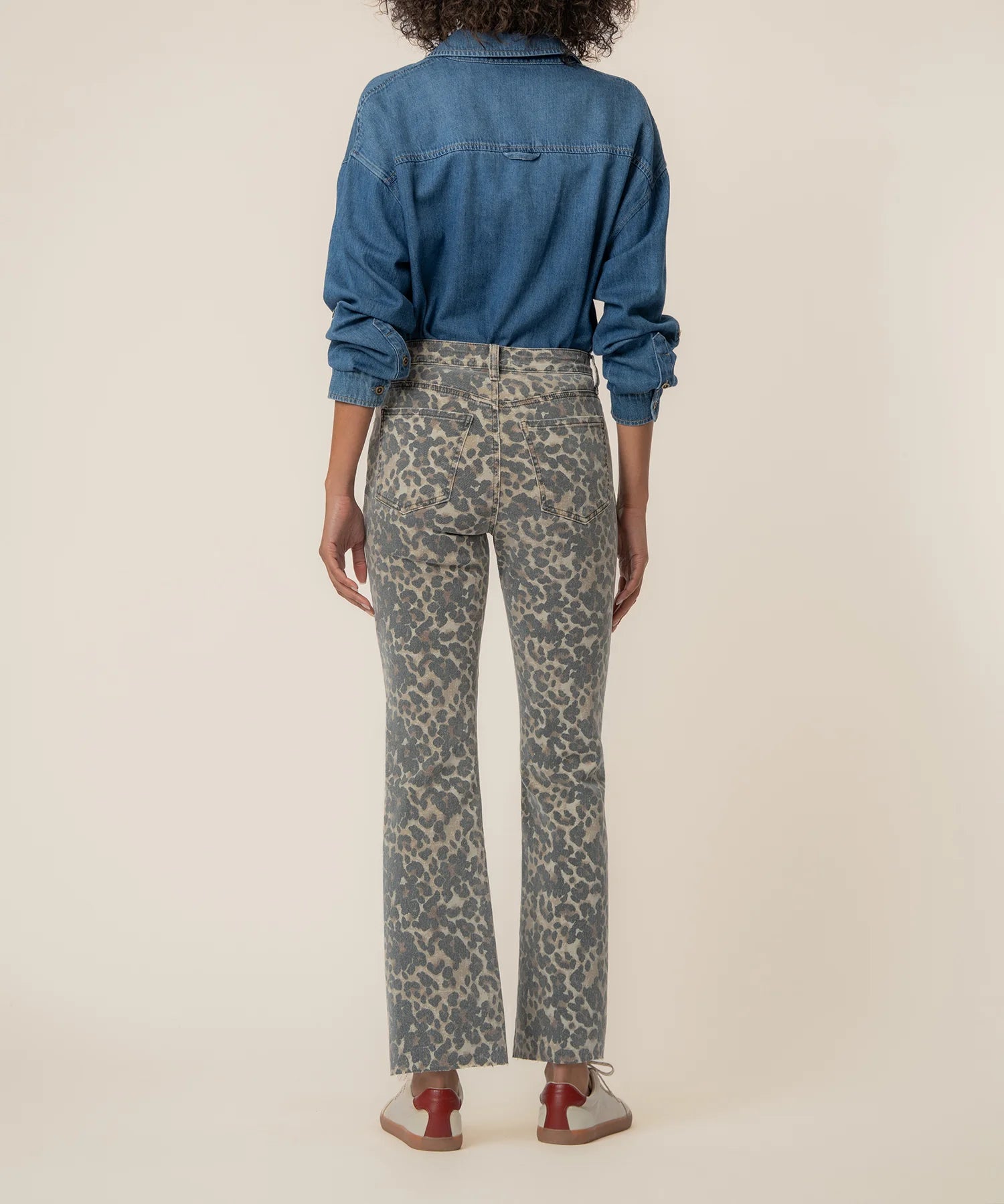 Person wearing a blue denim shirt and patterned pants on a beige background