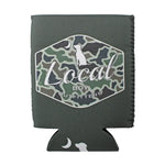 A dark gray neoprene can cooler sleeve featuring a central hexagonal patch with a green and black camouflage pattern, a white dog silhouette, and the text 'Local Boy Outfitters'. The sleeve has a stitched edge and a matching dark gray bottom tab with white moon and dog graphics.