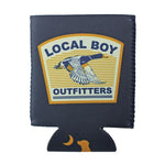 A navy blue koozie sleeve featuring a front patch that reads 'LOCAL BOY OUTFITTERS' with a flying duck graphic, and a small dog silhouette near the bottom edge.