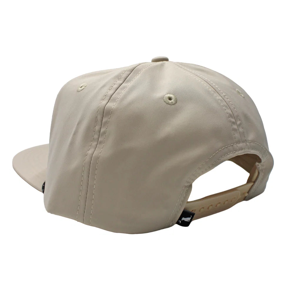 A light beige baseball cap shown from a rear three-quarter angle, featuring a structured six-panel crown, a flat brim, and an adjustable fabric back strap with a small black tag.