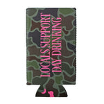 A neoprene can cooler sleeve featuring a green, brown, and black camouflage pattern with vertical pink text reading 'LOCALS SUPPORT DAY DRINKING' and a small pink silhouette at the bottom, shown on a plain white background.
