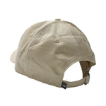 A light beige baseball cap shown from a rear three-quarter angle, featuring a curved brim and an adjustable snapback strap with a small black brand tag.