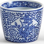A small white ceramic cup or planter with a blue floral and geometric pattern, shown against a plain white background.