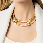 Gold chain necklace worn by a person against a neutral background