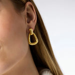 Gold hoop earring worn by a person with a neutral background