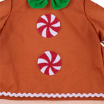 Close-up of an orange-brown garment or costume panel with two red-and-white swirl candy graphics and a white scalloped trim along the bottom edge.