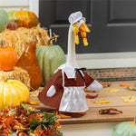 Giddy the Goose wearing a female Pilgrim outfit displayed on a front porch with pumpkins and fall harvest décor.