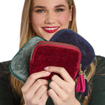 Woman holding three colorful zippered pouches with tassels.
