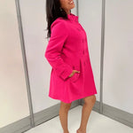 Women's hot pink honeycomb-textured statement coat with double-breasted covered buttons, high neckline, long sleeves, and front pockets.