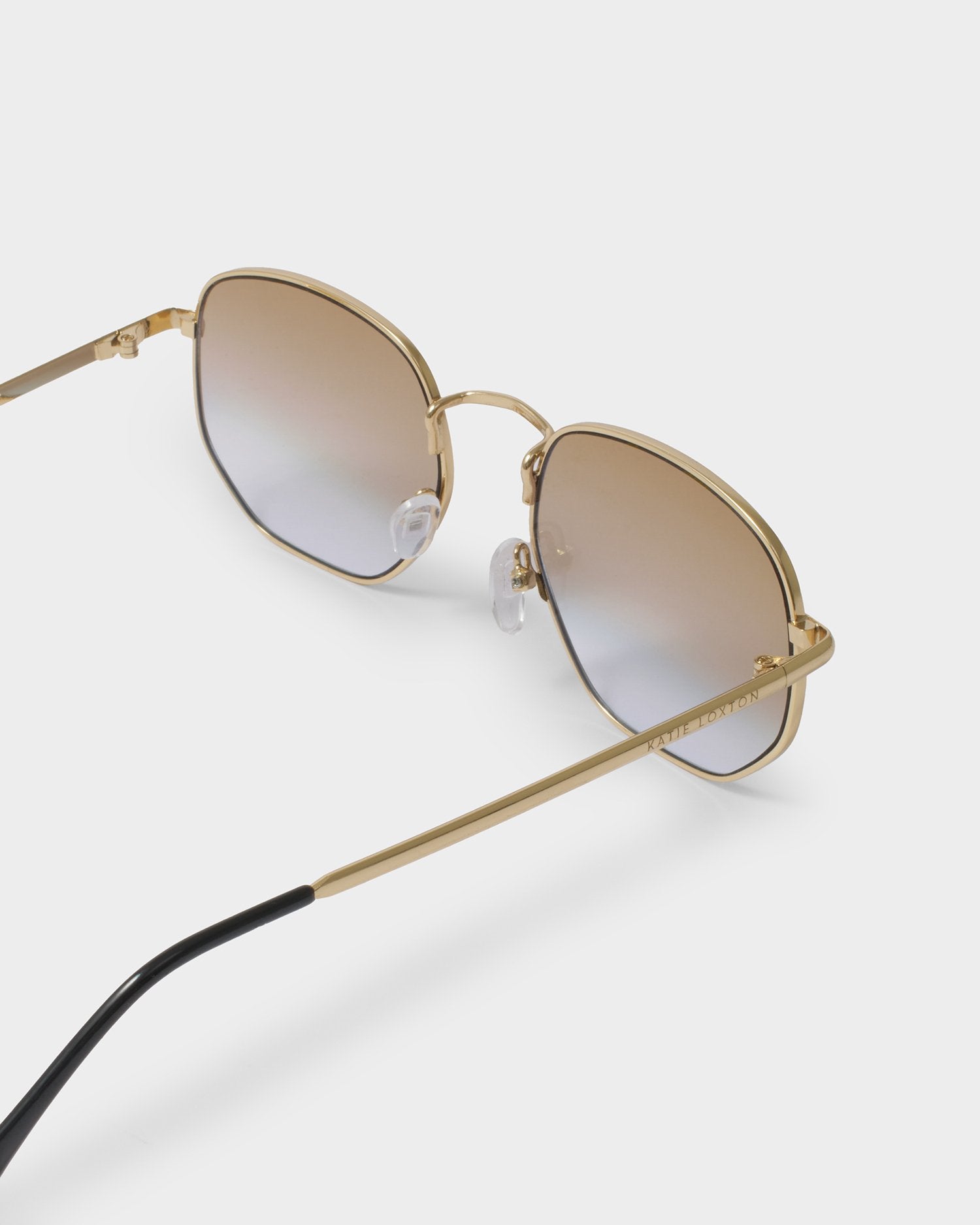 Gold-framed sunglasses with gradient lenses on a light gray background